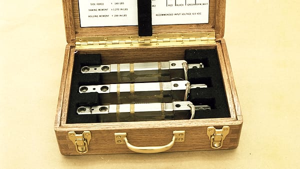 A steel bench holding a boxy instrument with a mouthpiece tube and a small printer beside a rack of sealed glass vials.