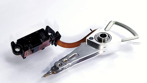 A dismantled handset on an anti-static mat beside a ribbon cable, a write-blocking adapter and a coiled USB lead.