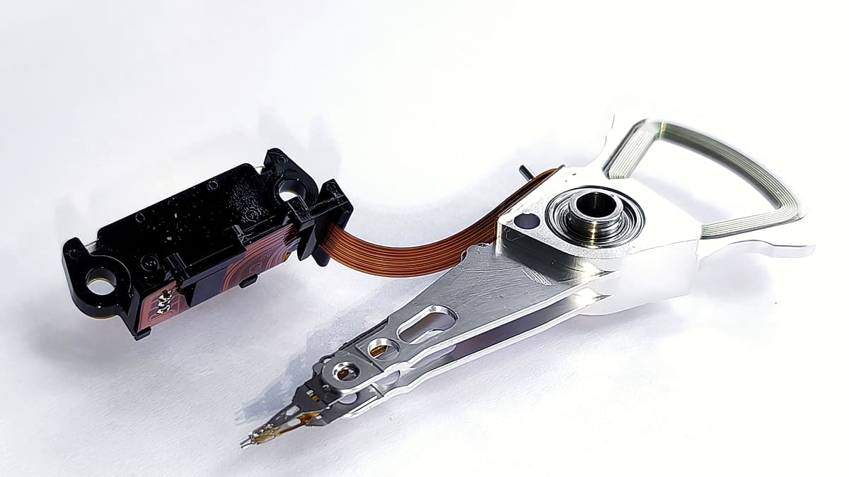 A dismantled handset on an anti-static mat beside a ribbon cable, a write-blocking adapter and a coiled USB lead.