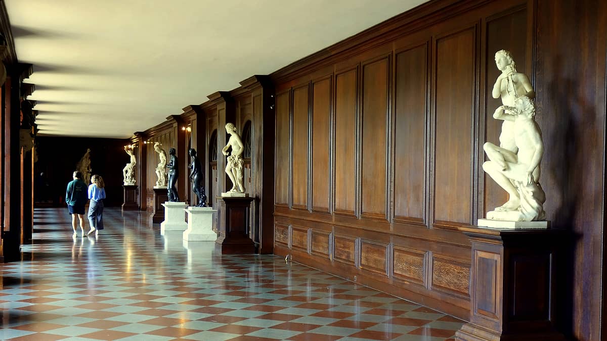 A jury box of empty upholstered seats behind a wooden rail, lit from a high window, the room otherwise still